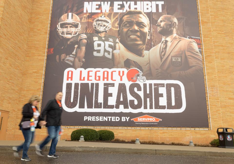 Fans walk by a banner at the Pro Football Hall of Fame for its newest exhibit, "A Legacy Unleashed," which honors the history of the Cleveland Browns.