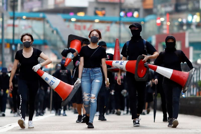 Protesters walk down the road with traffic cones to build a barricade in Causeway Bay