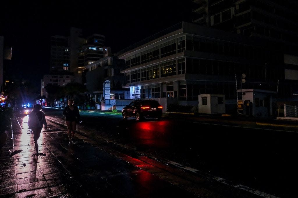 Cars lights illuminate an otherwise dark street in the Condado community of Santurce in San Juan on Sept. 19, amid power outages following Hurricane Fiona.