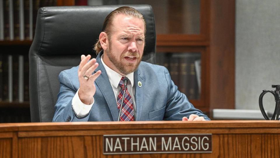 Fresno County Supervisor Nathan Magsig sits in a high back black leather chair and gestures with one hand.
