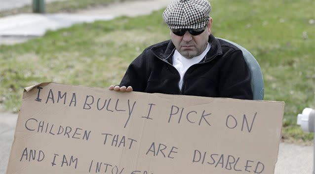 Edmond Aviv sits on a street corner holding a sign Sunday, April 13, 2014, in South Euclid, Ohio declaring he's a bully, a requirement of his sentence because he was accused of harassing a neighbour and her disabled children for the past 15 years. Photo: AP.