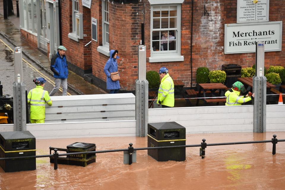 Environment agency workers put up flood defences in floodwater after the River Severn bursts it's banks in Bewdley, west of Birmingham on February 16, 2020, after Storm Dennis caused flooding across large swathes of Britain. - As Storm Dennis sweeps in, the country is bracing itself for widespread weather disruption for the second weekend in a row. Experts have warned that conditions amount to a "perfect storm", with hundreds of homes at risk of flooding. (Photo by Oli SCARFF / AFP) (Photo by OLI SCARFF/AFP via Getty Images)