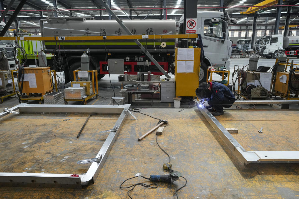 A worker weirds on a frame for liquid tanker trucks at a Yizhuan Automobile Co. manufacturing factory during a media-organized tour in Shiyan city in central China's Hubei Province on May 12, 2023. China's manufacturing and consumer spending are weakening after a strong start to 2023 after anti-virus controls ended. (AP Photo/Andy Wong)