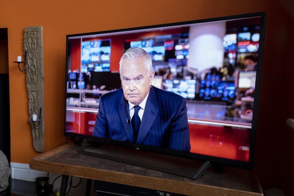 BBC News anchor wearing black Huw Edwards announces the death of Queen Elizabeth II on a screen at a home