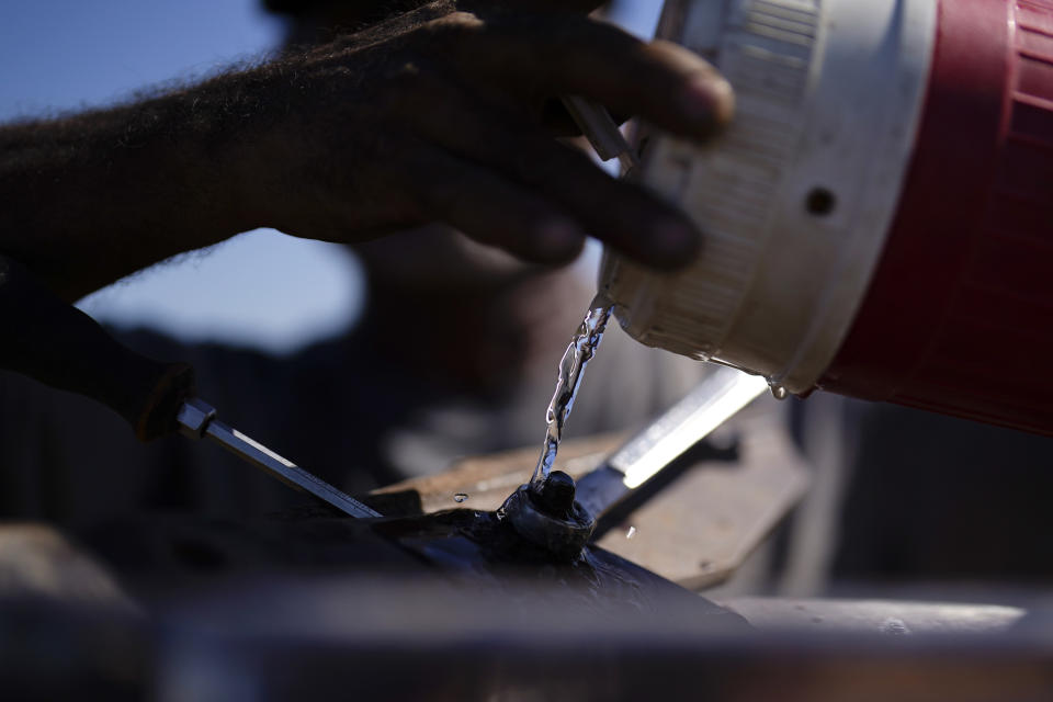 Jose Garcia pours water on bolt as he works to remove a broken blade on a plow on a farm irrigated with water from the Colorado River, Sunday, Aug. 14, 2022, near Los Algodones, Mexico. By the time the Colorado River reaches Mexico, just a fraction of its water is left for the fields of the Mexicali Valley and millions of people in northwestern desert cities. (AP Photo/Gregory Bull)