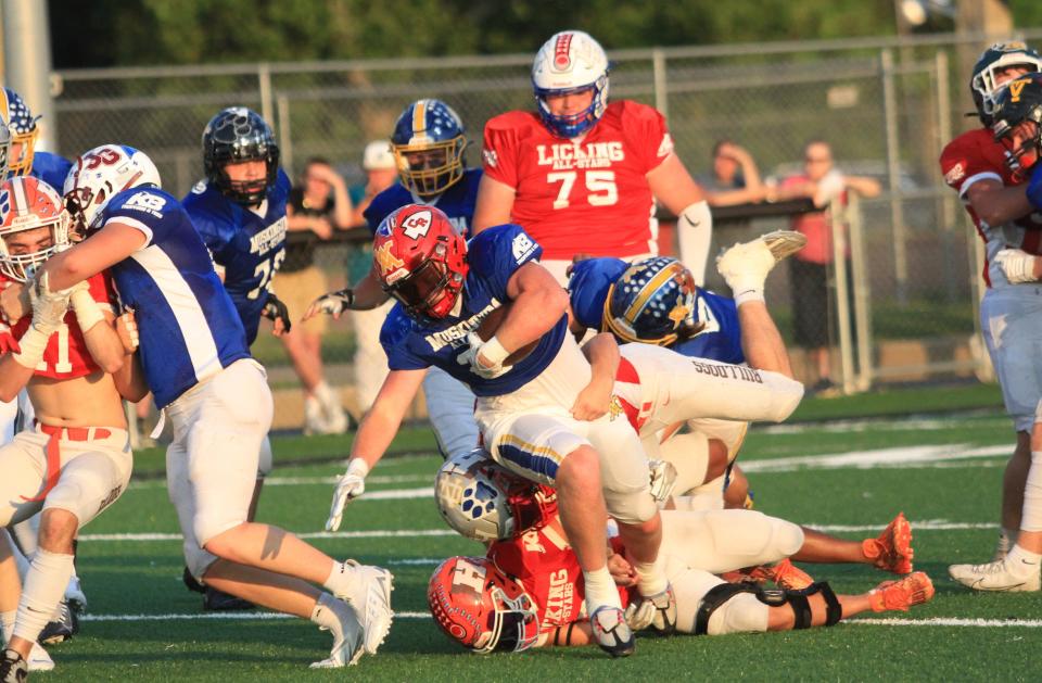 Coshocton's Riley Woodie attempts to break through the tackle of Utica's Tyler Collura and Heath's Grayson Shumate during Muskingum Valley's 40-26 victory against Licking County on Friday.