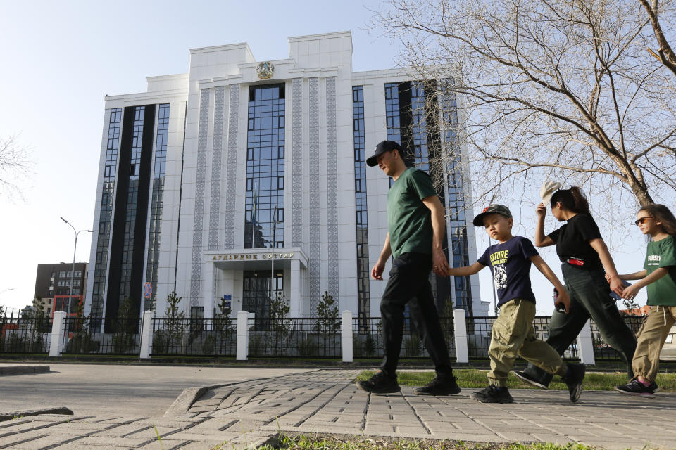 A family walks past the courthouse where the trial of former Economics Minister Kuandyk Bishimbayev is taking place in Astana, Kazakhstan, on Sunday, April 21, 2024. Bishimbayev, charged with killing his wife, Saltanat Nukenova, has touched a nerve in the Central Asian country. Tens of thousands of people have signed petitions calling for harsher penalties for domestic violence, and on April 11, senators approved a bill toughening penalties for spousal abuse, and President Kassym-Jomart Tokayev signed the measure into law four days later. (AP Photo/Stanislav Filippov)