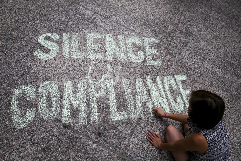 A woman writes "Silence is Compliance" with a chalk on the ground at Federal Plaza Square in Chicago during an&nbsp;Aug. 13 protest in response to the violence that erupted in Charlottesville.