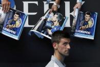 Novak Djokovic of Serbia walks past magazines featuring pictures of himself as he signs autographs after winning his men's singles match against Leonardo Mayer of Argentina at the Australian Open 2014 tennis tournament in Melbourne January 15, 2014. REUTERS/Jason Reed