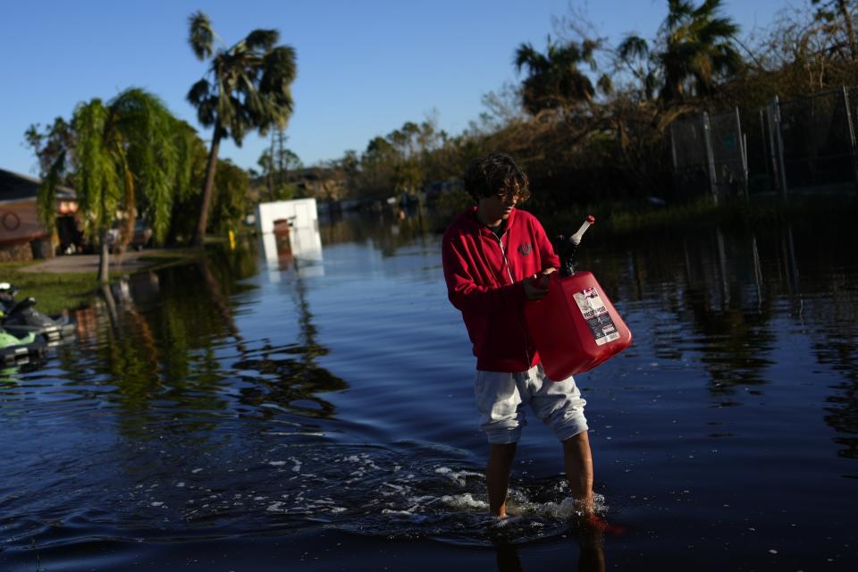 FILE - Jose Cruz, 13, carries an empty Jerrycan through receding flood waters outside his house as his family heads out to look for supplies, three days after the passage of Hurricane Ian, in Fort Myers, Fla., Oct. 1, 2022. After months of gradually warming sea surface temperatures in the tropical Pacific Ocean, NOAA officially issued an El Nino advisory Thursday, June 8, 2023, and stated that this one might be different than the others. (AP Photo/Rebecca Blackwell, File)