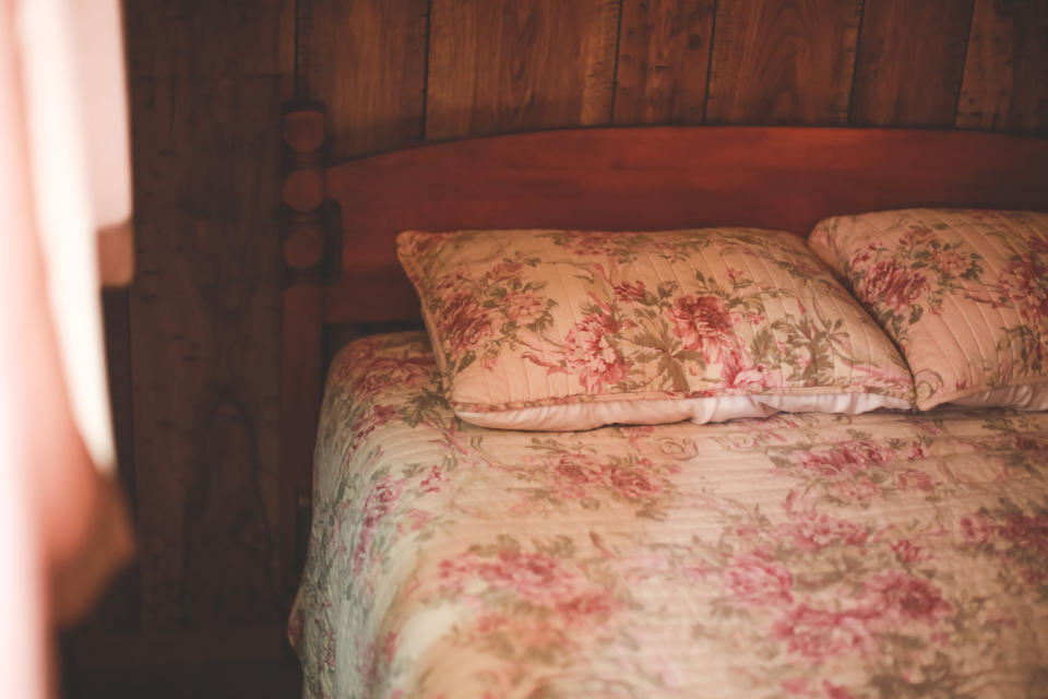 A comfy wooden room with a bottom featuring a floral-patterned bedclothes and matched pillows