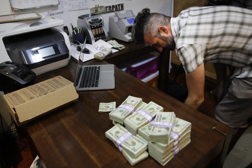 FILE - In this June 27, 2017, file photo, bundles of $20 bills are placed on a table as Jerred Kiloh, owner of the Higher Path medical marijuana dispensary, prepares a trip to Los Angeles City Hall to pay his monthly tax payment in cash in Los Angeles. The leading cannabis industry group in California announced Tuesday, Jan. 19, 2021, it had reached an agreement with a state credit union that will provide access to checking and other banking services for marijuana companies, ending what had been a longstanding obstacle for many businesses. (AP Photo/Jae C. Hong, File)