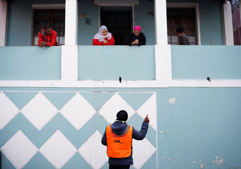 A health worker talks to residents as they conduct screening during the 21-day nationwide lockdown aimed at limiting the spread of coronavirus disease (COVID-19) in Bo Kaap, Cape Town