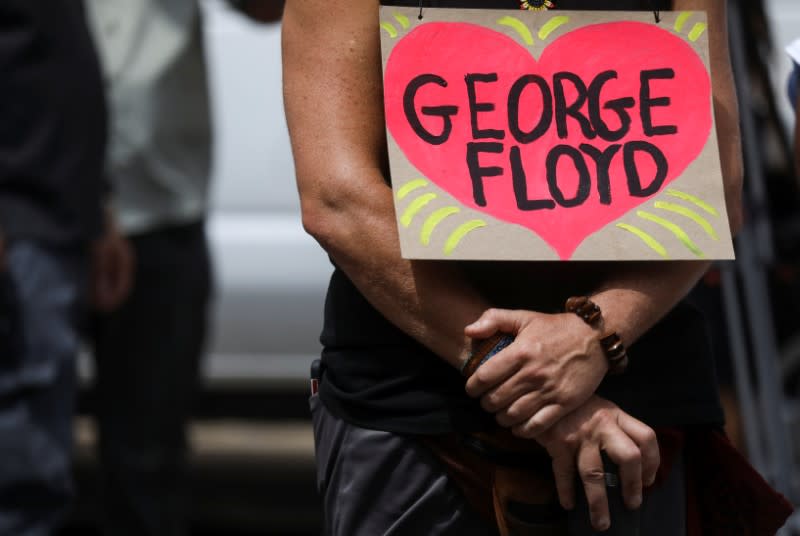 A person with a placard stands outside during a memorial service for George Floyd following his death in Minneapolis police custody, in Minneapolis