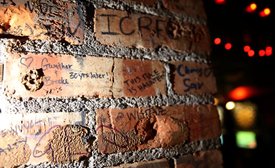 Signatures, some from 30 years ago, are pictured on the bricks at Alleycat, formerly Joystick Comedy Arcade and The Yacht Club, Tuesday, April 23, 2024 in downtown Iowa City, Iowa.