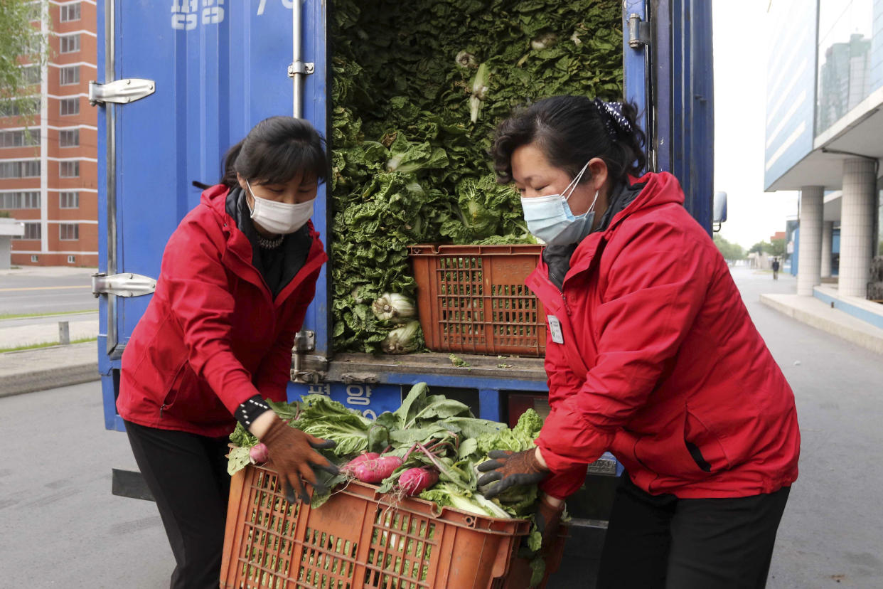 Greengrocers carry produce to supply to residents staying home as the state increased measures to stop the spread of illness in Pyongyang on Monday. (Jon Chol Jin / AP)