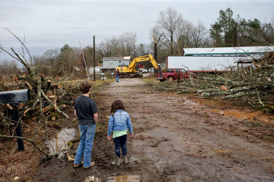 Jan 12, 2023; Tuscaloosa, AL, USA; A tornado heavily damaged homes and destroyed mobile homes on Oak Village Road near Akron in Hale County. Jake Tillie and his sister Raelynn Phillips watch as a track hoe clears debris. They were in school when the tornado struck.