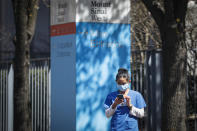 A medical worker uses her phone while wearing a surgical mask outside Mt. Sinai West, Thursday, March 26, 2020, in New York. The new coronavirus causes mild or moderate symptoms for most people, but for some, especially older adults and people with existing health problems, it can cause more severe illness or death. (AP Photo/John Minchillo)