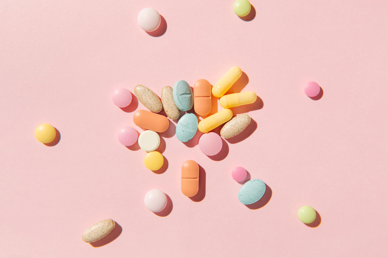 Colorful pills and capsules on pink background. 