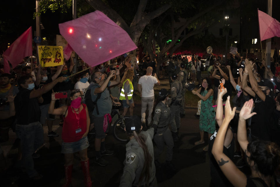 Israeli police officers try to block Israeli protesters during a demonstration against lockdown measures that they believe are aimed at curbing protests against prime minister Benjamin Netanyahu in Tel Aviv, Israel, Thursday, Oct. 1, 2020. (AP Photo/Sebastian Scheiner)