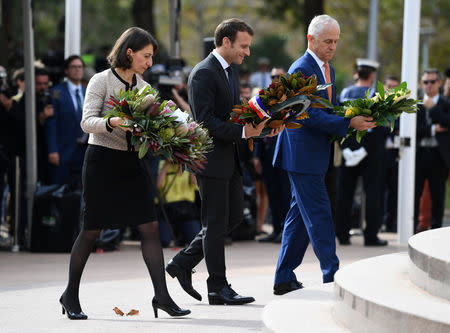 French President Emmanuel Macron walks carrying a floral wreath tribute with NSW Premier Gladys Berejiklian and Australian Prime Minister Malcolm Turnbull during a Commemorative Service at the ANZAC war memorial in Sydney, May 2, 2018. AAP/David Moir/via REUTERS