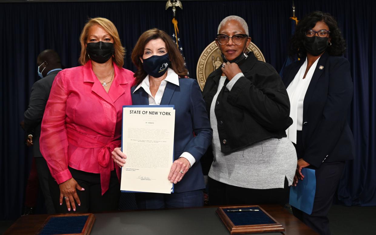 New York Gov. Kathy Hochul (center) with signed legislation of "Less is More" bill.