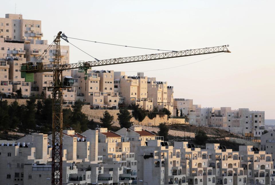 A crane is seen next to homes in a Jewish settlement near Jerusalem known to Israelis as Har Homa and to Palestinians as Jabal Abu Ghneim January 3, 2014. Israel on Friday published tenders for 1,400 new homes in the occupied West Bank and East Jerusalem, days after U.S. Secretary of State John Kerry visited the region to push peace efforts with the Palestinians. Picture taken January 3, 2014. REUTERS/Ammar Awad (BUSINESS CONSTRUCTION POLITICS)