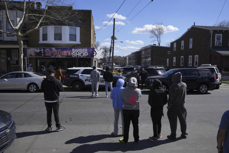 People look on as police surround a home in Trenton, N.J., Saturday, March 16, 2024. A suspect has barricaded himself in the home and was holding hostages after shooting three people to death in suburban Philadelphia. (AP Photo/Matt Rourke) (AP Photo/Matt Rourke)