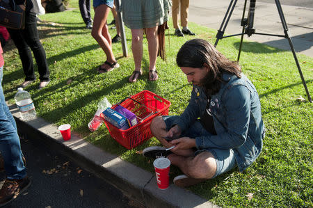 Matthew Foley sits next to the grocery basket he carried with him when he fled a hostage situation in a Trader Joe's store, in Los Angeles, California, Saturday July 21, 2018. Foley's girlfriend was in the bathroom when the suspect entered the store and was trapped in the building for roughly three hours as police cleared the scene. REUTERS/Andrew Cullen