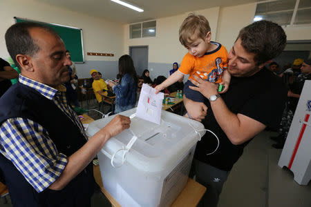 A child casts a ballot on behalf of his father during the parliamentary election in Tibnin, Lebanon, May 6, 2018. REUTERS/Aziz Taher