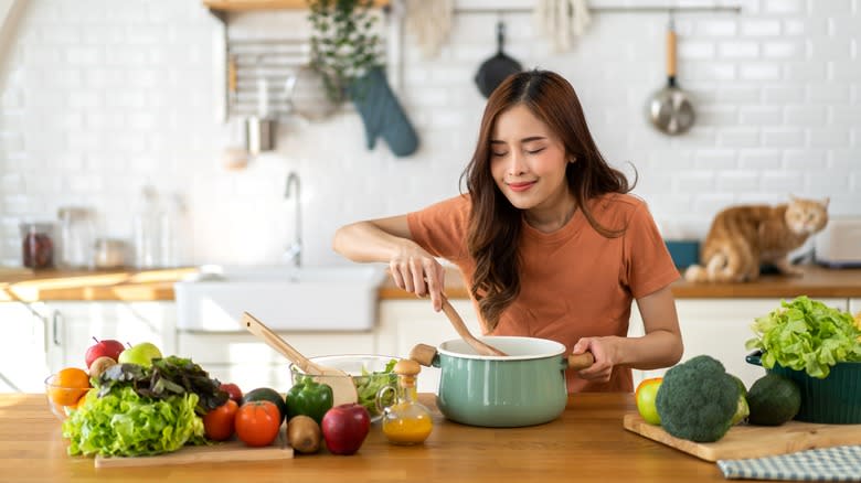 woman smelling pot of soup