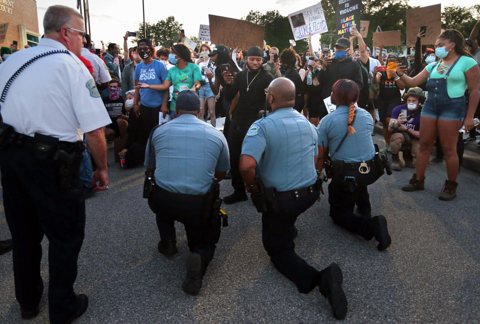 FILE - In this May 30, 2020, file photo, police officers from Ferguson, Mo., join protesters to remember George Floyd by taking a knee in the parking lot of the police station. Floyd, a black man, died after being restrained by Minneapolis police officers on May 25 and his death sparked protests. Black officers find themselves torn between two worlds when it comes to the protests against police brutality happening around the U.S. (Robert Cohen/St. Louis Post-Dispatch via AP, File)