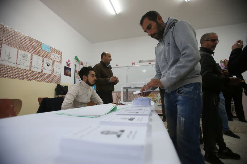 A voter receives ballots at a polling station during the presidential election in Algiers