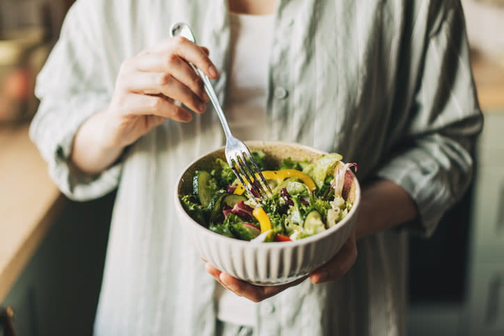 Person eating a fresh salad with a fork