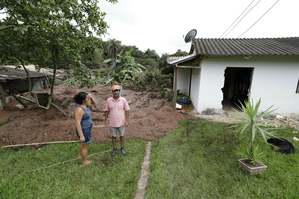 Residents Pedro de Jesus Rocha and wife Isamara de Araujo stand outside their partially destroyed house after a dam collapsed, in Brumadinho, Brazil, Saturday, Jan. 26, 2019. An estimated 300 people were still missing and authorities expected the death toll to rise during a search made more challenging by intermittent rains. (AP Photo/Andre Penner)