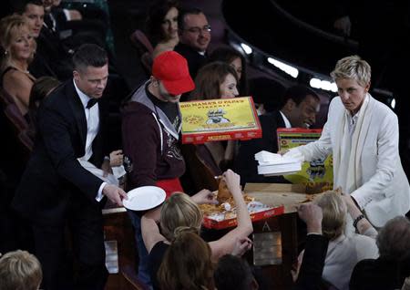 Show host Ellen DeGeneres (R) delivers pizza to the audience as actor Brad Pitt (L) hands out paper plates at the 86th Academy Awards in Hollywood, California March 2, 2014. REUTERS/Lucy Nicholson