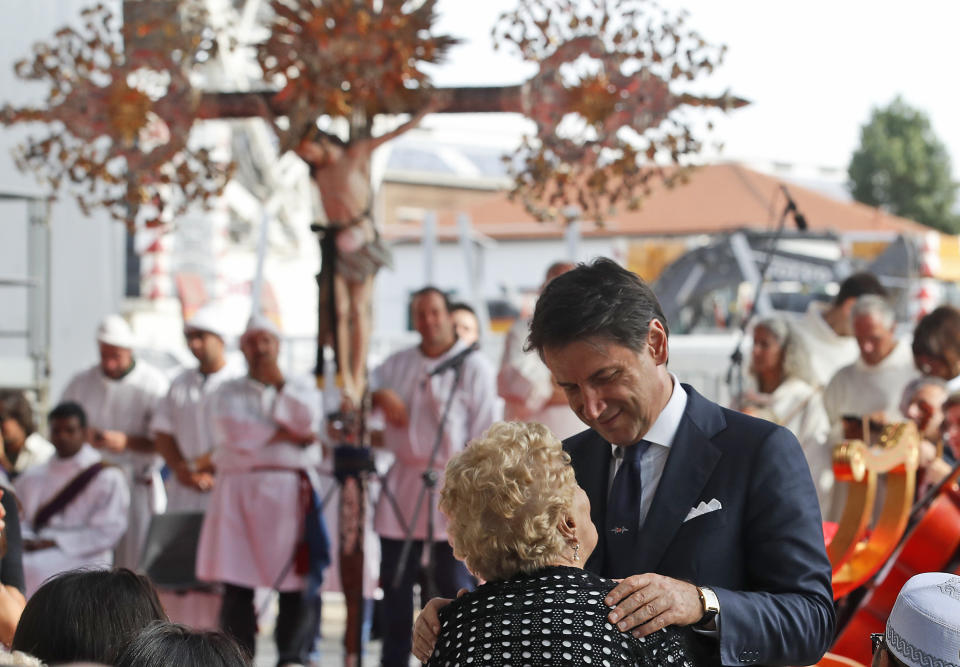 Italian Premier Giuseppe Conte embraces a relative of a victim of the Morandi bridge collapse, during a remembrance ceremony to mark the first anniversary of the tragedy, in Genoa, Italy, Wednesday, Aug. 14, 2019. The Morandi bridge was a road viaduct on the A10 motorway in Genoa, that collapsed one year ago killing 43 people. (AP Photo/Antonio Calanni)