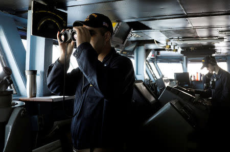 A U.S. Navy personnel looks through a pair of binocular at the bridge of USS Carl Vinson during a FONOPS (Freedom of Navigation Operation Patrol) in South China Sea, March 3, 2017. REUTERS/Erik De Castro