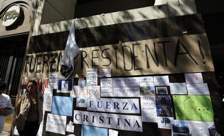 A woman waits next to signs in support of Argentina's President Cristina Fernandez outside the hospital where she had surgery in Buenos Aires October 8, 2013. REUTERS/Marcos Brindicci