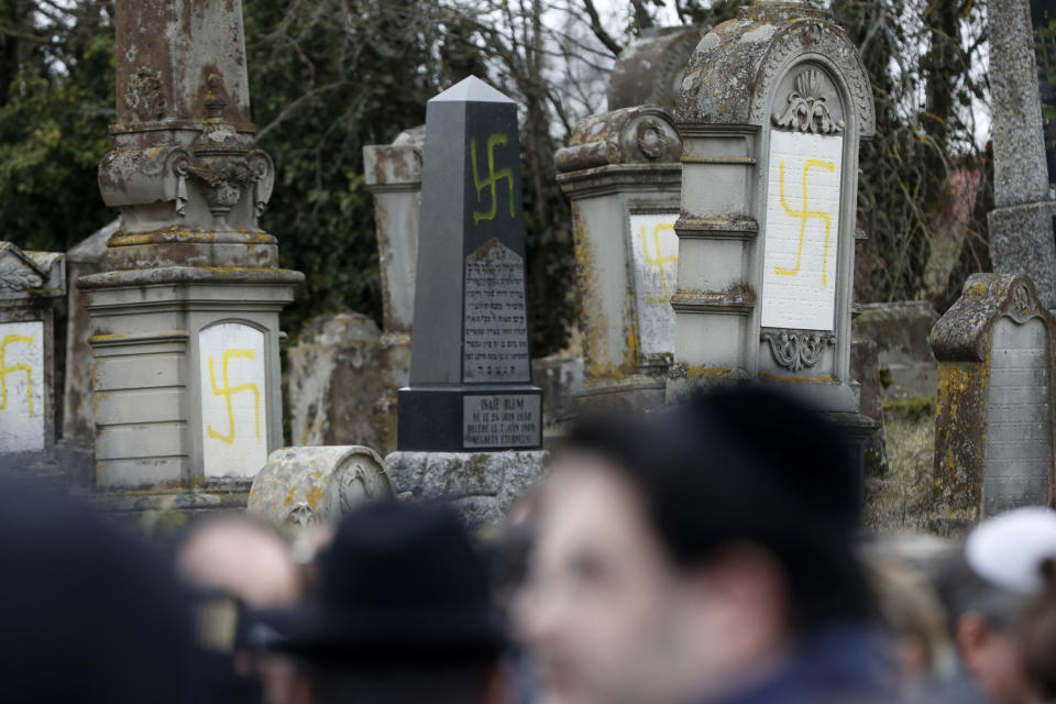 Members of the Jewish community gather at the Jewish cemetery where tombs were tagged with swastikas in Quatzenheim, eastern France, Tuesday, Feb.19, 2019. Marches and gatherings against anti-Semitism are taking place across France following a series of anti-Semitic acts that shocked the country. (AP Photo/Jean-Francois Badias)