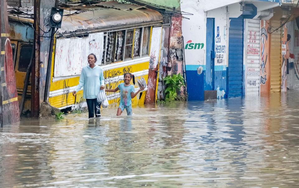 eople walk through a street flooded by the rains of Tropical Storm Franklin in Santo Domingo, Dominican Republic, on Tuesday.