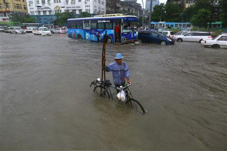 A man pushes his bicycle through flood waters in central Yangon, August 22, 2013. REUTERS/Soe Zeya Tun