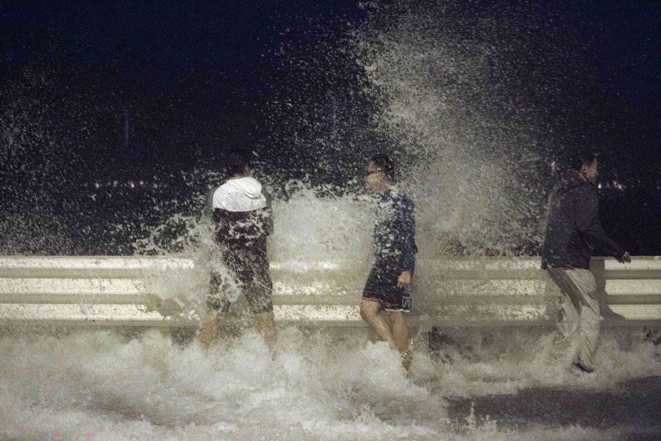 People react as waves splash on to the road during Typhoon Usagi in Hong Kong September 22, 2013. A powerful typhoon headed towards the southern Chinese city of Hong Kong, one of the most densely populated cities on Earth, on Sunday amid warnings of severe flooding as well as strong winds in the event of a direct hit. REUTERS/Tyrone Siu