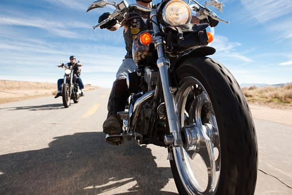 Two people riding motorcycles on highway.