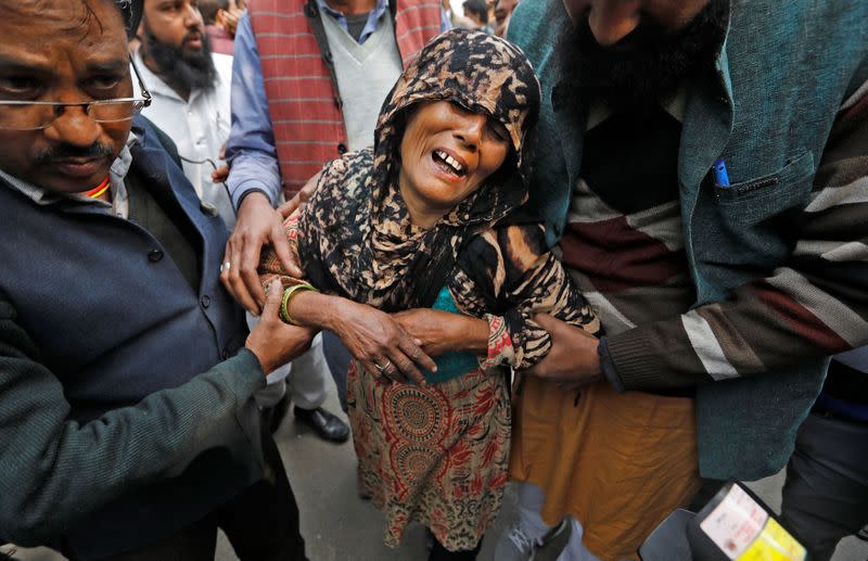 A woman cries as she waits outside a mortuary to receive the body of her relative who died in a fire that swept through a factory where labourers were sleeping on Sunday, in New Delh