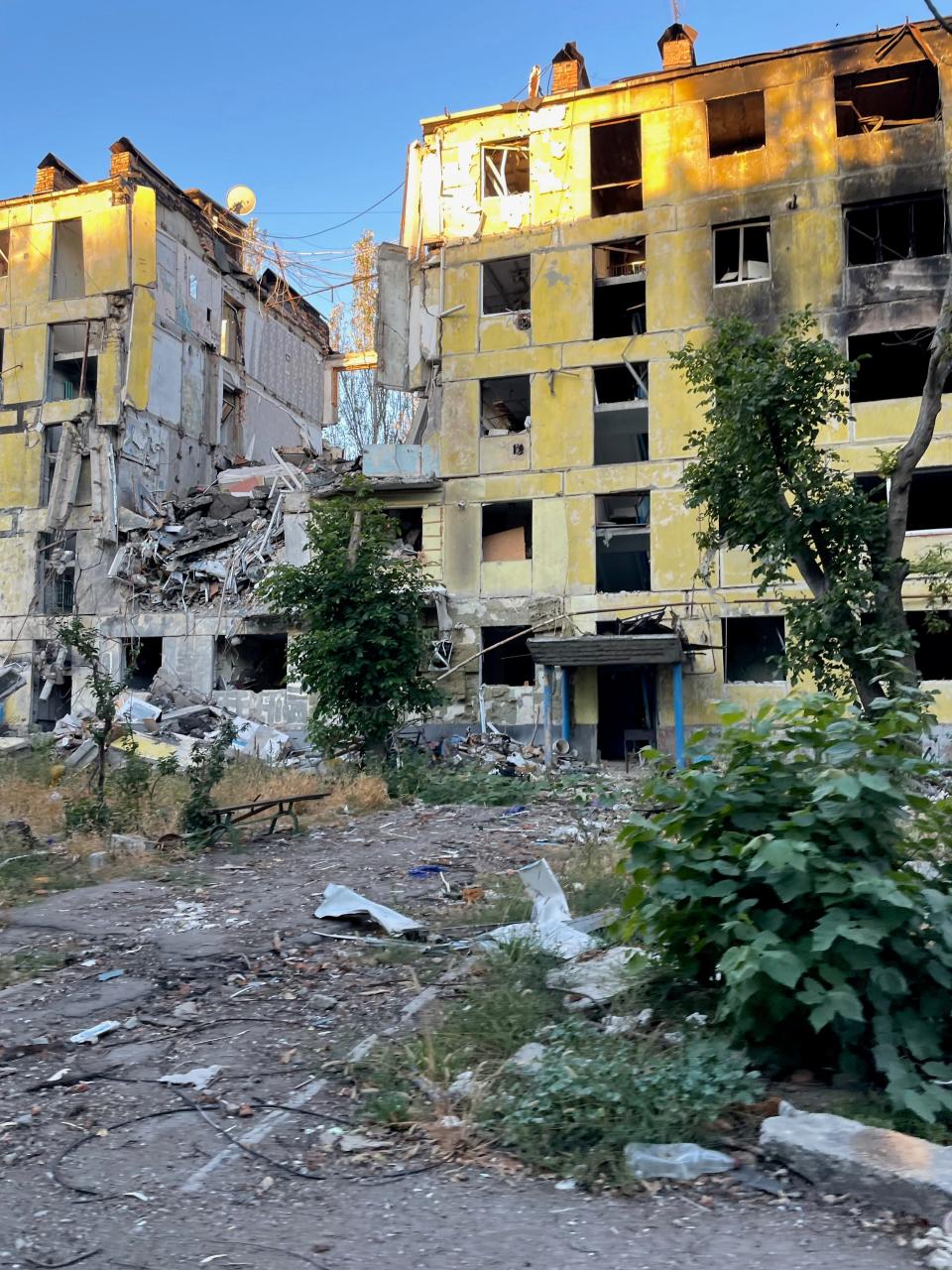 a yellow 5-story building that has collapsed in the middle and looks burnt out