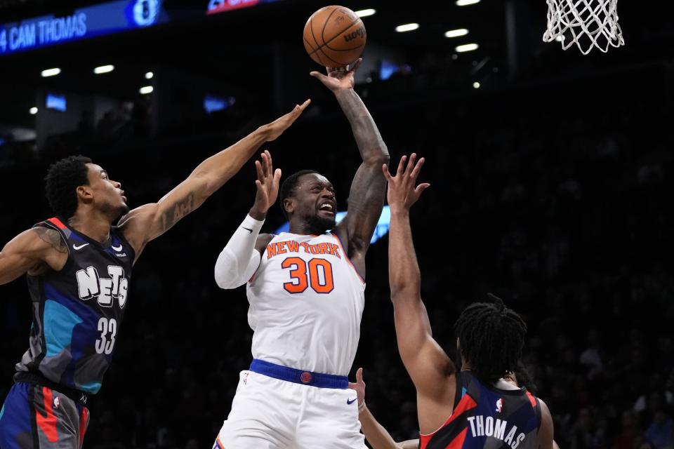 New York Knicks' Julius Randle, center, shoots over Brooklyn Nets' Nic Claxton, left, and Cam Thomas, right, during the first half of an NBA basketball game Wednesday, Dec. 20, 2023, in New York. (AP Photo/Frank Franklin II)