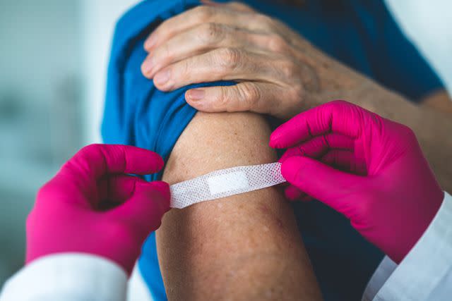 <p>Getty</p> Doctor puts a bandaid on a patient after a vaccination.