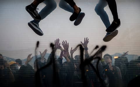 Protesters climbing over a highway dividers fleeing from police arrests as their comrades help on the other side during a demonstration - Credit: PA