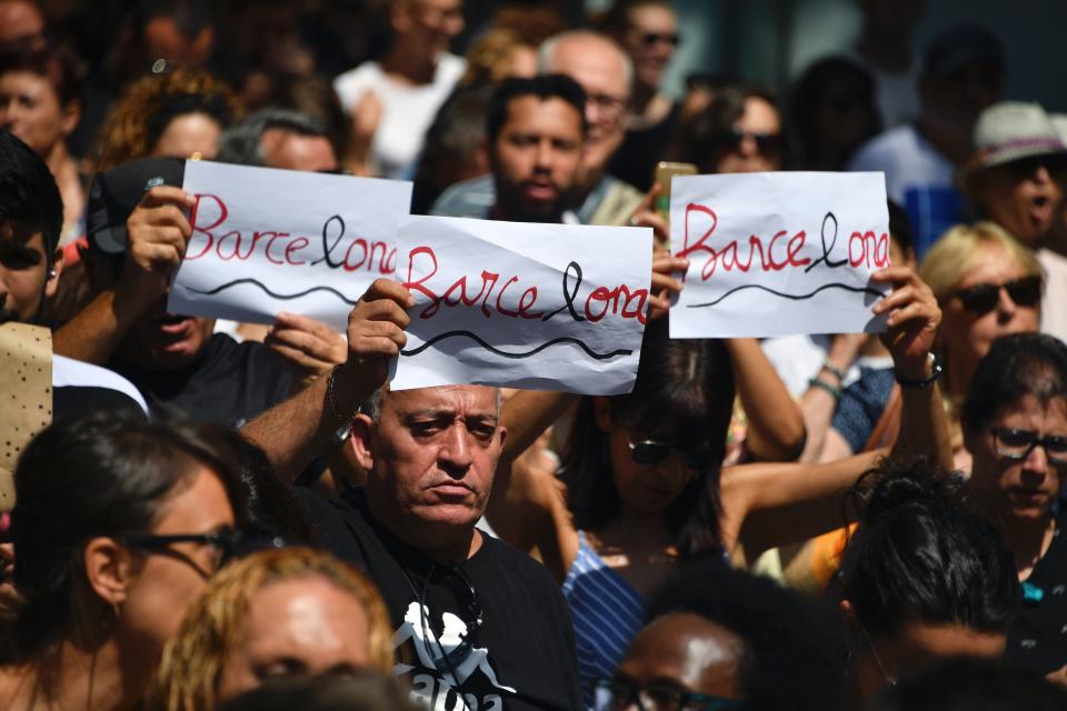 People hold aloft written signs displaying Barcelona's name before observing a minute of silence.